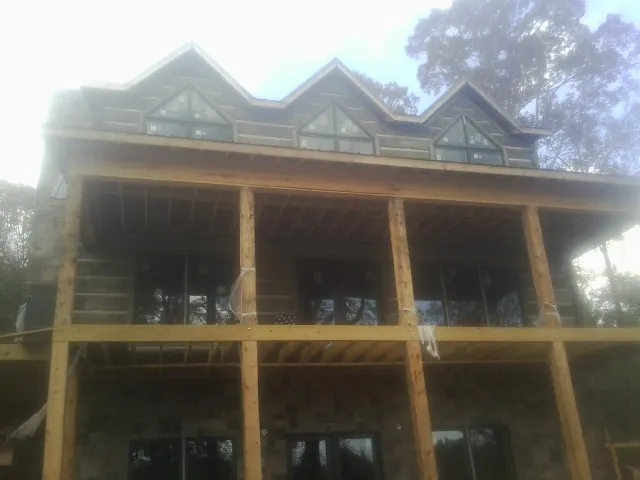 Dormers and porch framing on a large log home under construction — Roof Coating work by our crew in Perry